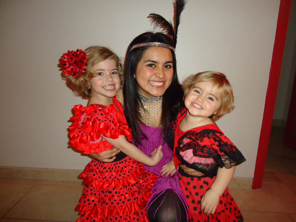 Au pair mexicana disfrazada y abrazando a las dos niñas de su familia anfitriona