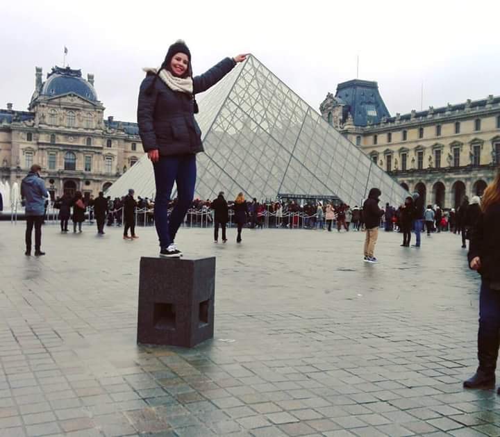 Au pair mexicana posando frente a la pirámide del Museo del Louvre en París