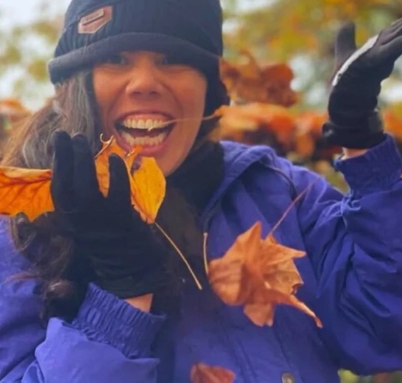 Laura sonriendo y jugando con hojas de otoño durante su año en Estados Unidos